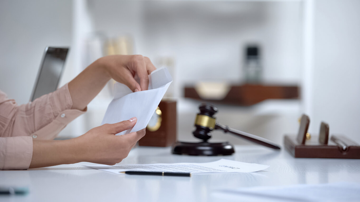 Persons hands pulling something out of an envelope with a gavel in the background